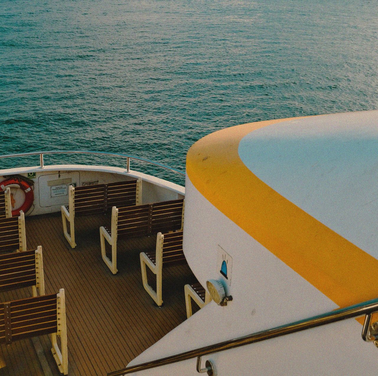 About A luxury cruise ship deck with wooden seats and calm sea view, perfect for summer travel.